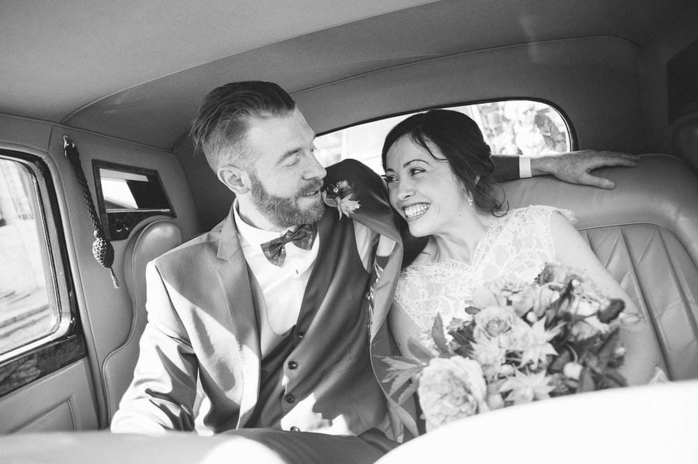 bride and groom in back of wedding car 