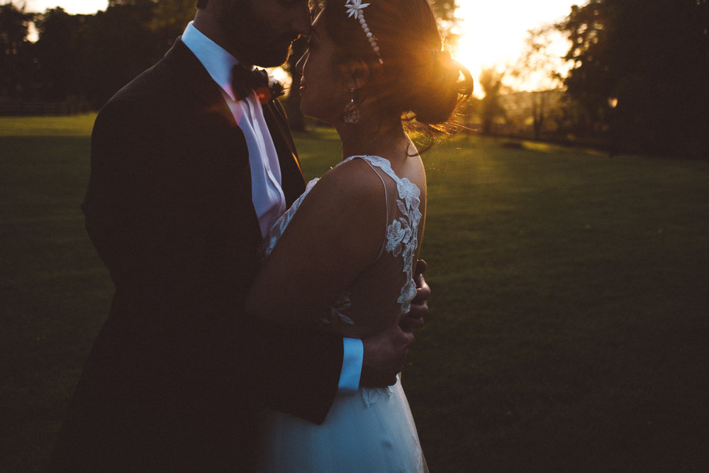 close up of grooms hands hugging brides back at sunset 
