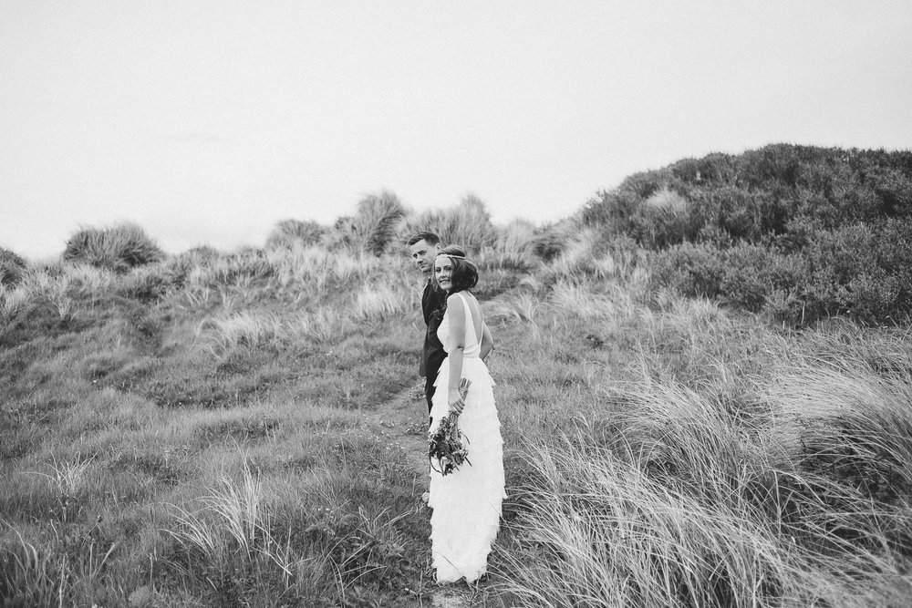 bride and groom stand in long grass