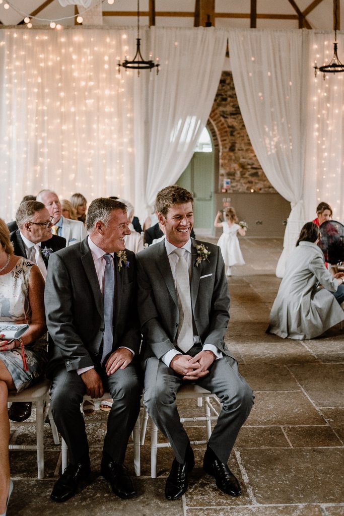 groom waits at the top of the aisle 