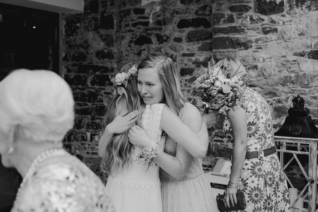 bridesmaid hugs the bride crying 