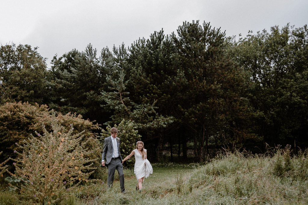bride and groom walk out in long grass 