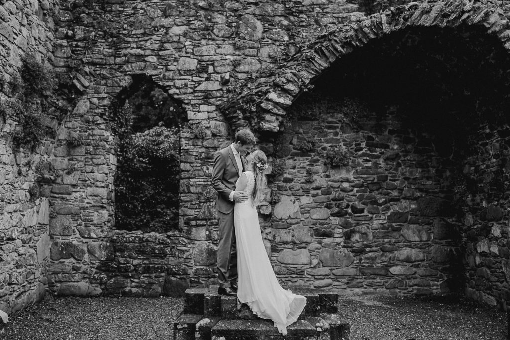 bride stands on wall and dress hangs down 