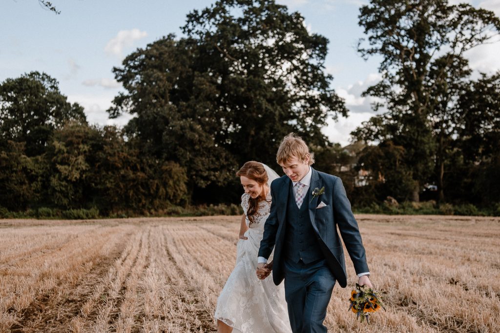 bride and groom walking into a field