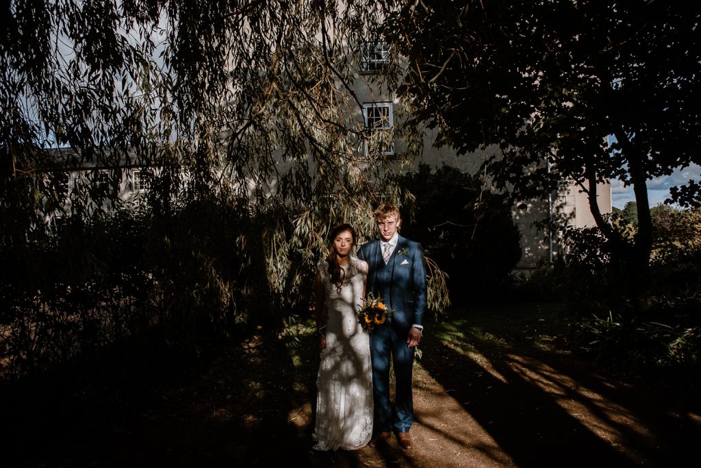 bride and groom standing among shadows and lights