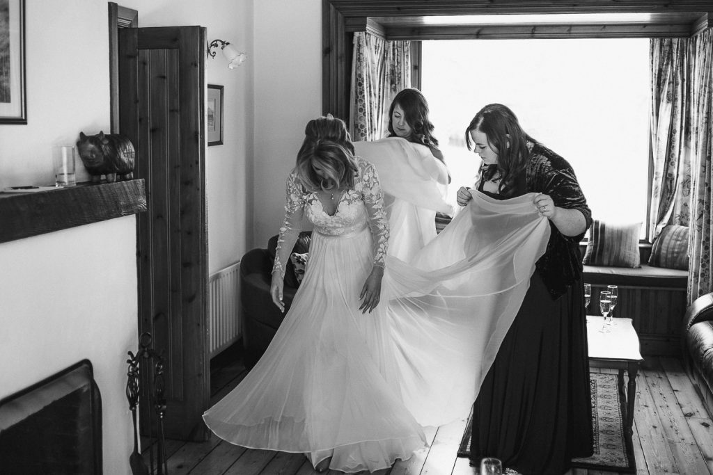bridesmaids fixing brides dress 