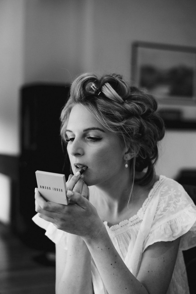 bride looking in small mirror putting on lipstick