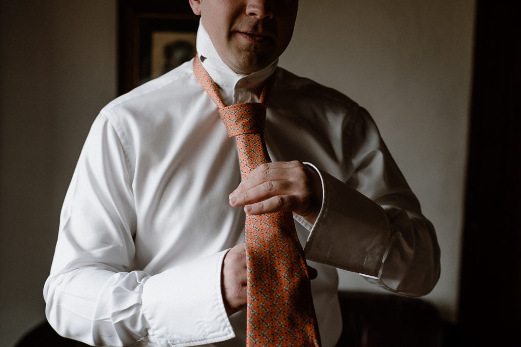close up of groom doing tie 