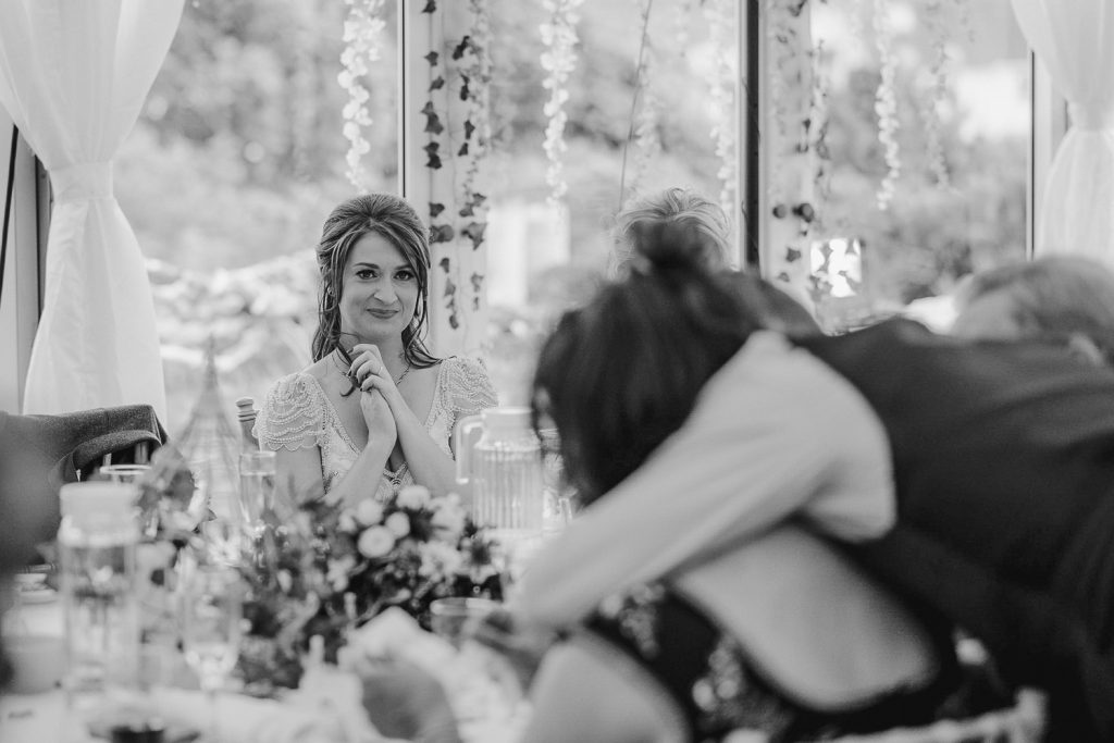 bride looks on as groom hugs his mother 