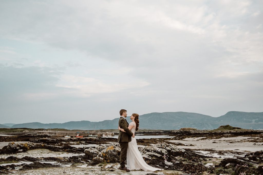 bead and groom facing each other on beach