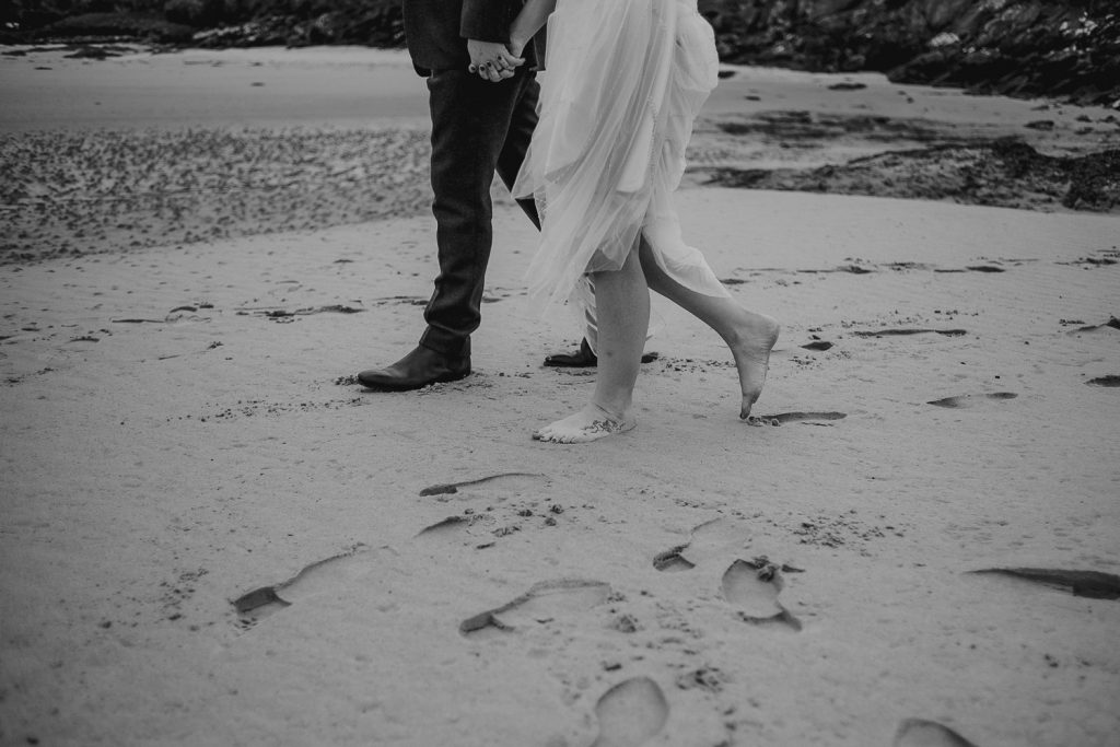 close up of bride walking barefoot on sand 
