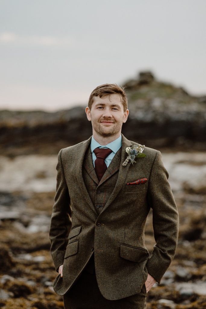 groom smiling with hands in pockets 