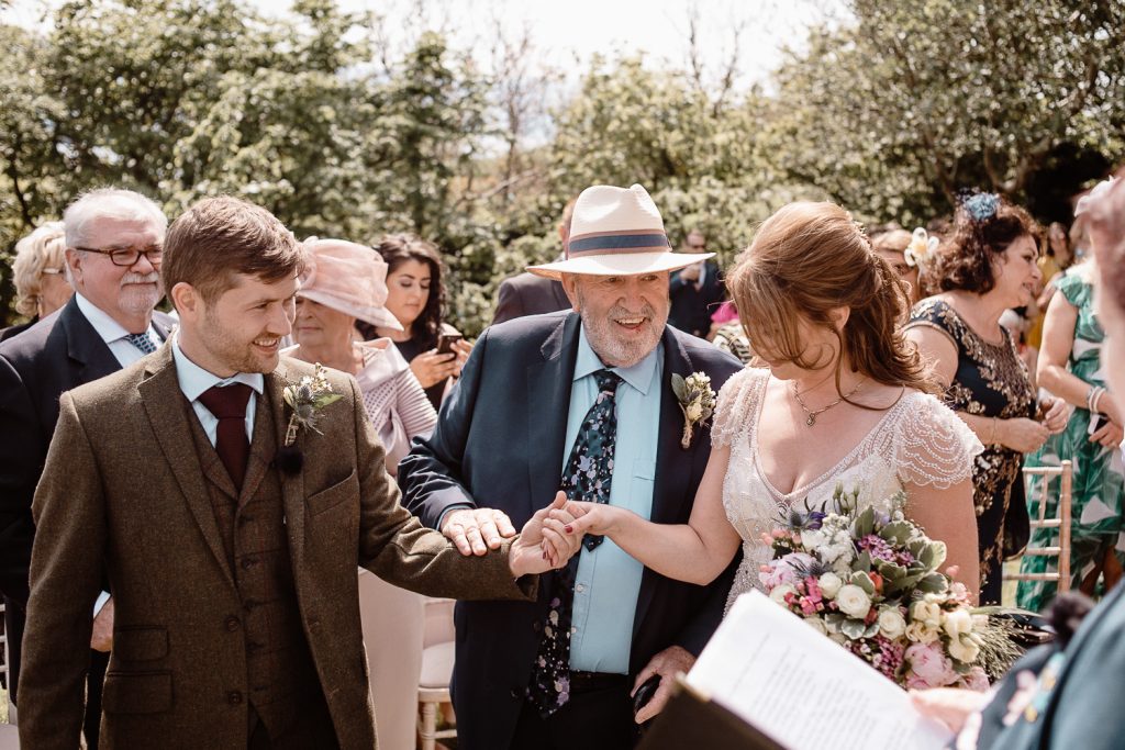 brides father gives her hand to groom