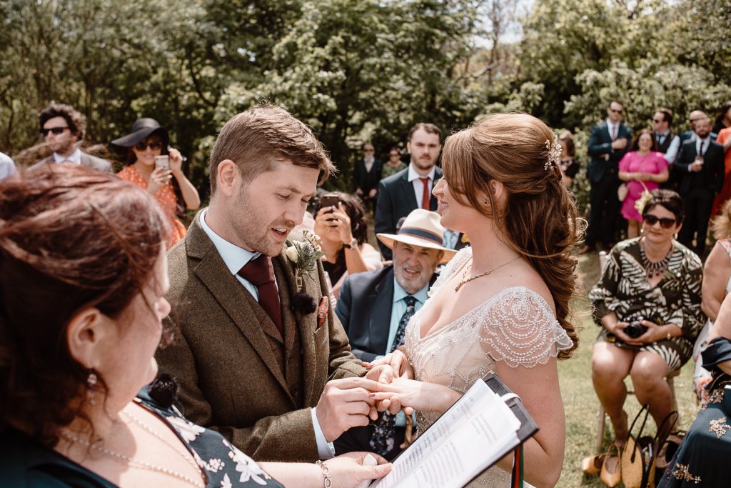 groom putting ring on bides finger 