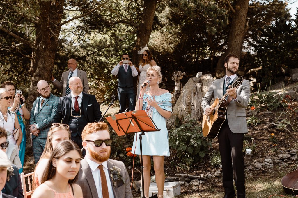 guests singing at wedding outside 