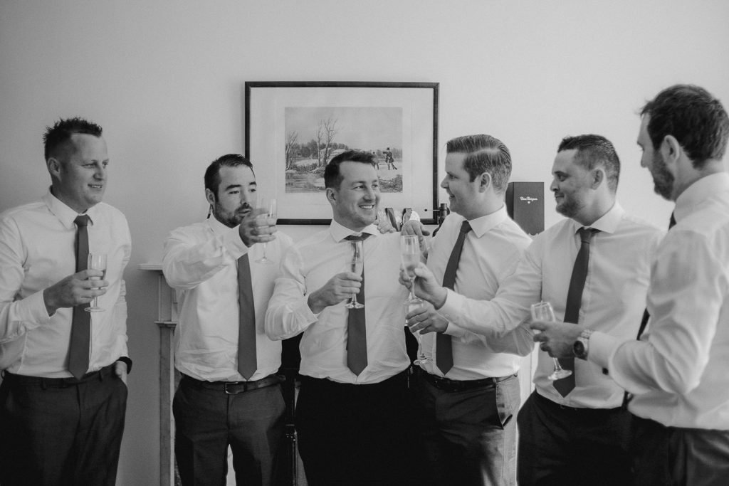 groomsmen and groom toasting a drink