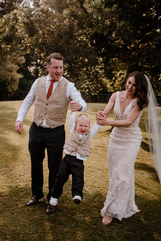 bride and groom swinging their son and he cries