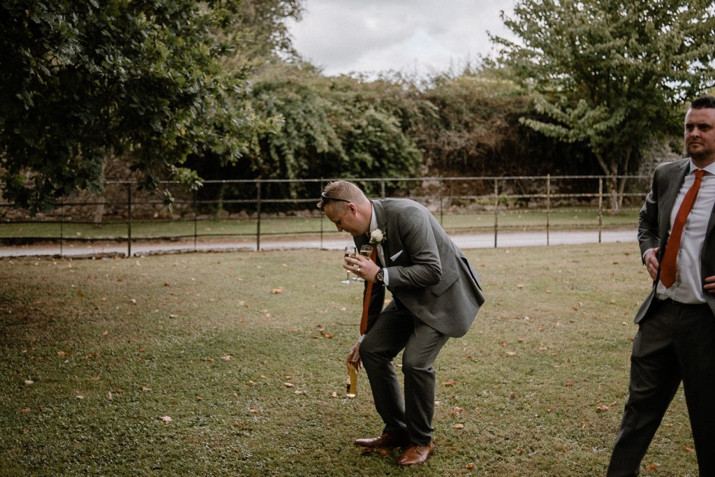 best man sets down drink on grass